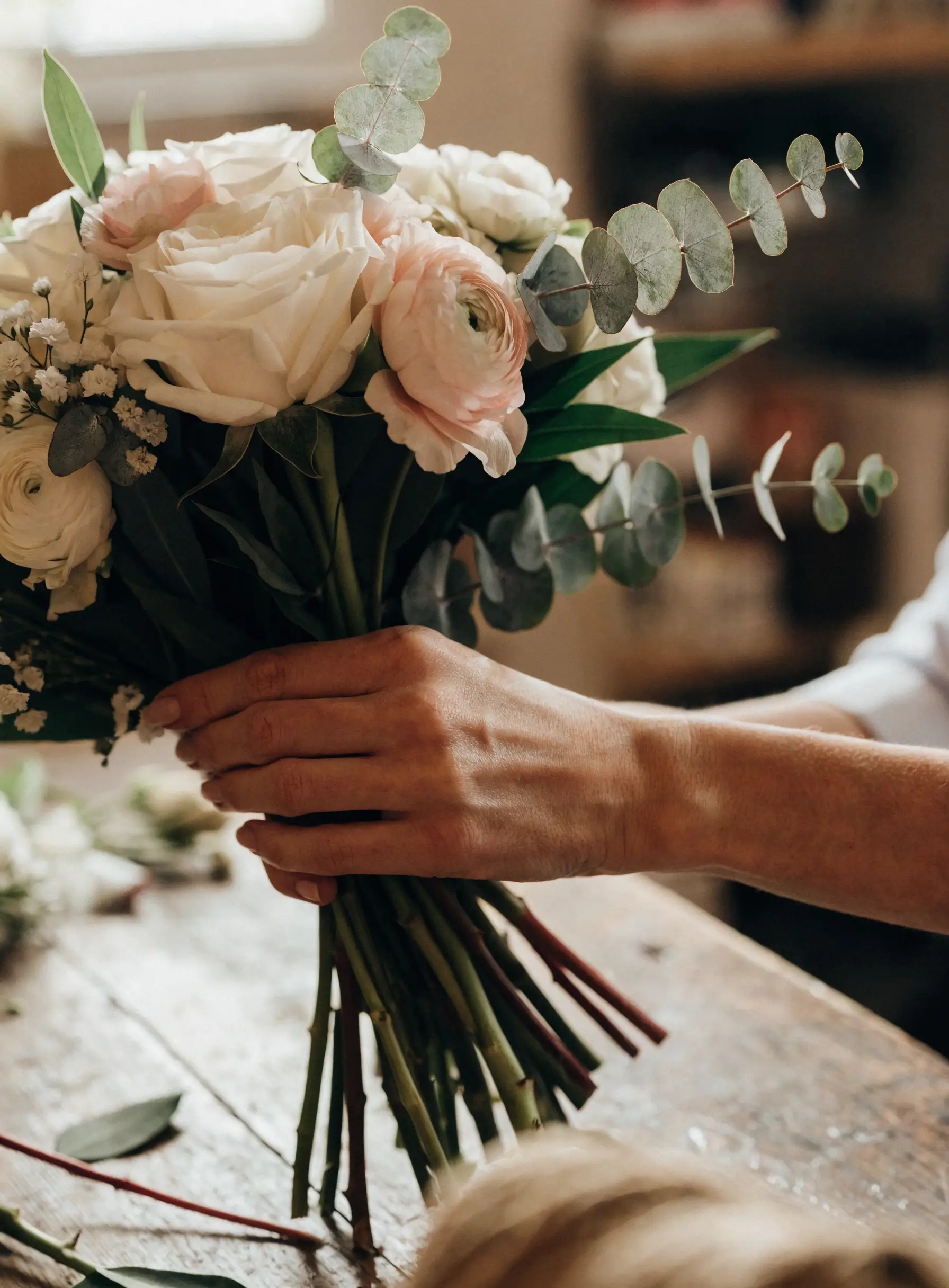 A florist arranging a cream bridal bouquet