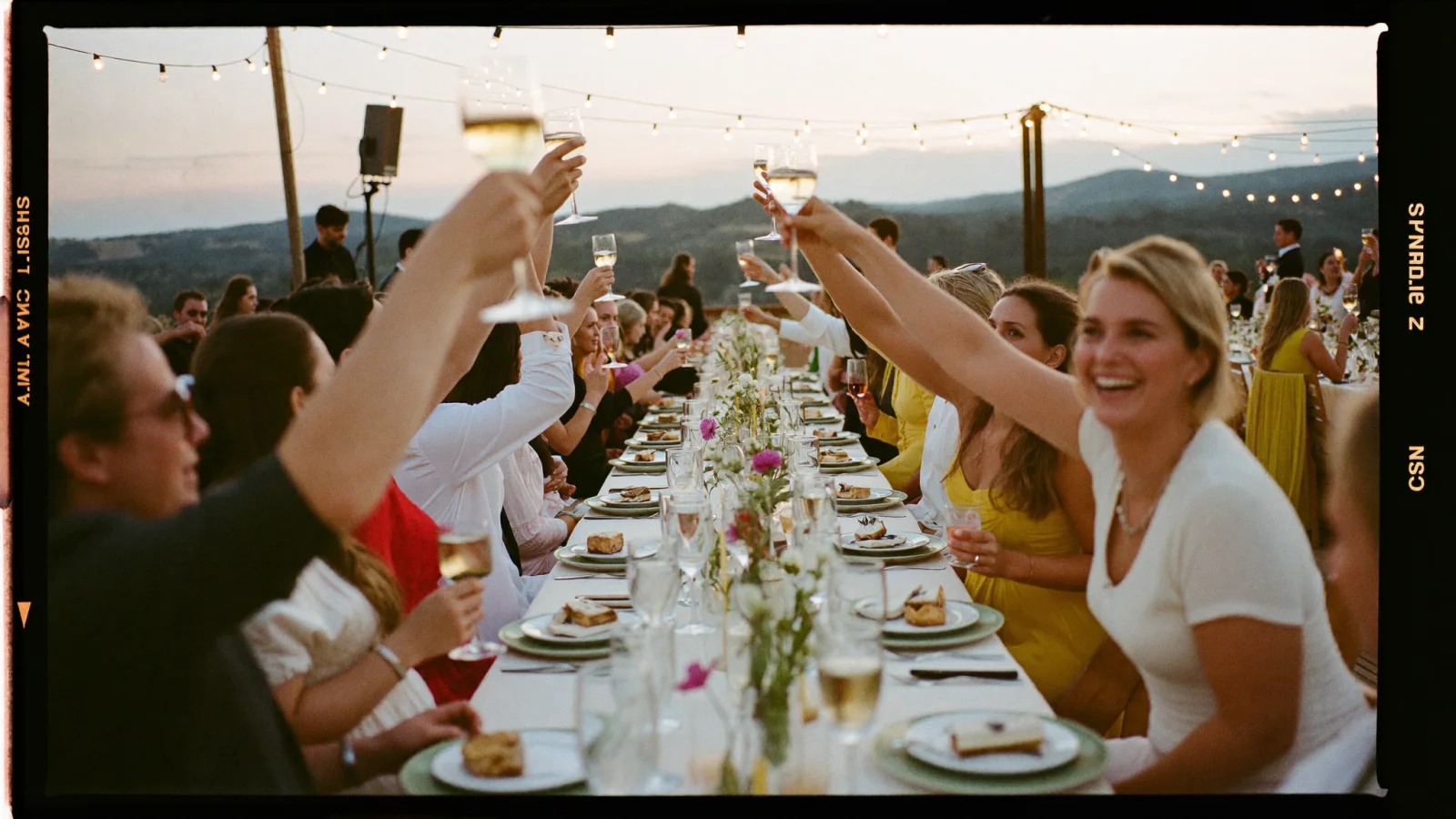 Guests toasting at a golden-hour outdoor wedding reception